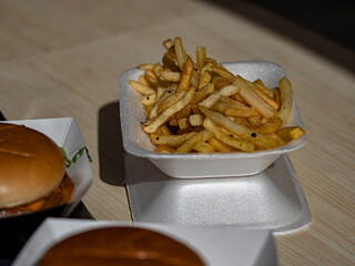 Chips and burgers in polystyrene containers on the counter of a takeaway fast food stall at a market
