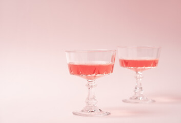 Two crystal glasses of rose sparkling wine or champagne on pastel pink background. Summer drink concept. Minimal creative composition with copy space.