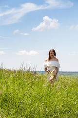 Fototapeta premium Young woman is holding bouquet of wildflowers and smiling. Freedom of movement and enjoyment of nature. Selective focus.