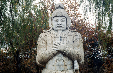 Fototapeta na wymiar Ornate stone-carved Chinese warrior statues in a park near the Ming Tombs, northwest of Beijing, China. Warrior