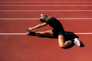 girl sitting on track stretching her legs