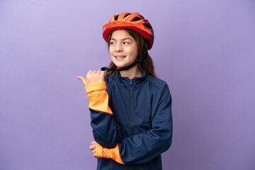 Little caucasian girl isolated on purple background pointing to the side to present a product