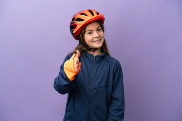 Little caucasian girl isolated on purple background shaking hands for closing a good deal