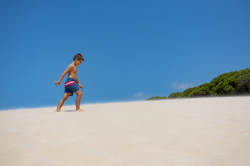 Fototapeta na wymiar Little boy walking down a dune on a spanish beach