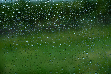 Drops of water flow down the surface of the clear glass on a black background. Texture for creativity.