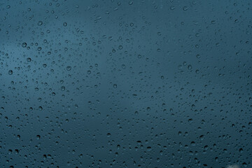Drops of water flow down the surface of the clear glass on a black background. Texture for creativity.