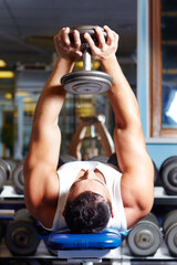 Strengthening his triceps. A muscular young man working out in the gym.