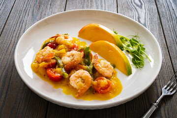 Prawns in mango sauce on wooden table

