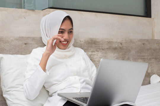 asian muslim woman using her laptop computer in the room
