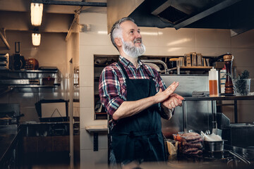 Happy old man chef in kitchen thinking about food