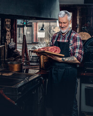Joyful old chef posing in old fashioned meat grocery