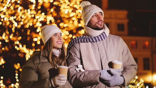 winter holidays, hot drinks and people concept - happy couple with takeaway coffee in disposable paper cups talking in city on christmas