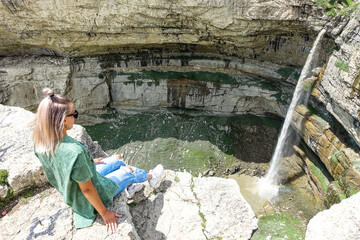 Fototapeta na wymiar Girl on the background of Tobot waterfall, Khunzakh waterfalls, Dagestan Russia 2021
