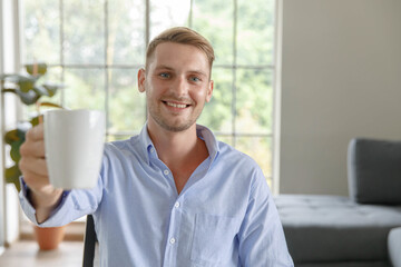 Portrait shot millennial caucasian male businessman in casual outfit sitting smiling look at camera in front of computer waving hand say hello greeting customer in webinar video distance conference