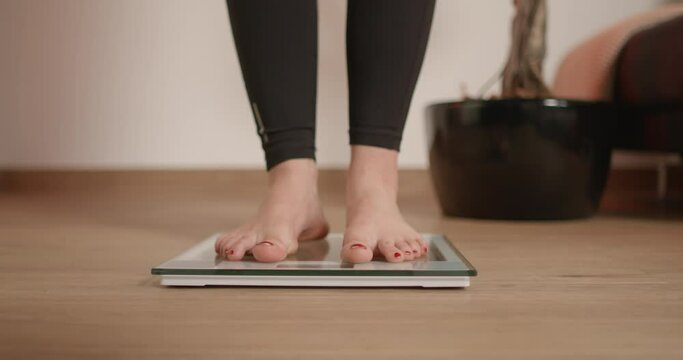 Female stepping on scale and wiggling her toes while checking her weight