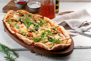 Long seafood pizza with shrimp, squid, mussels and olives on a wooden board	