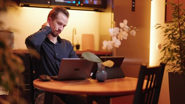 Businessman behind the laptop computer in kitchen with pain in neck work at home 4K