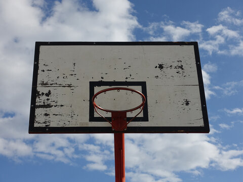 Basketball hoop on an outdoor court with sky and clouds  background