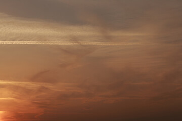 Sunset sky, clouds illuminated by the sun. Contrails and feather clouds. 