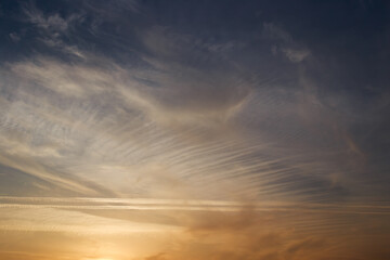 Fototapeta na wymiar Sunset sky, clouds illuminated by the sun. Contrails and feather clouds. 