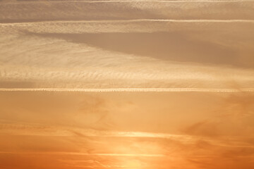 Sunset sky, clouds illuminated by the sun. Contrails and feather clouds. 