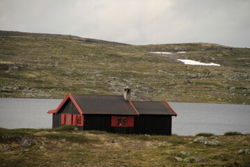 skandinaviesche landschaft mit haus am Wasse un Bergen