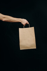 paper bags in hands on a black background