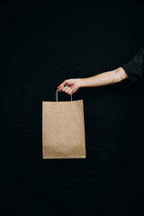 Fototapeta na wymiar paper bags in hands on a black background