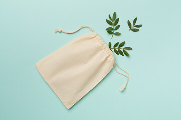 Small eco sack with green leaves on color background. Top view