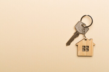 Keys with house-shaped keychain on color background