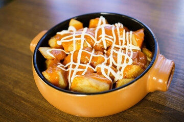 Plate of patatas bravas, a typical Spanish dish, on restaurant table