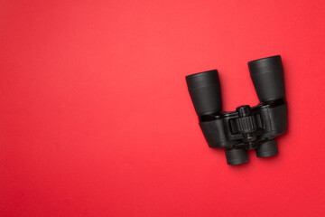 Black binoculars on color background. Top view