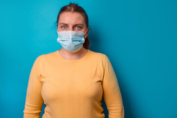 30s woman in a protective medical mask on a blue background.