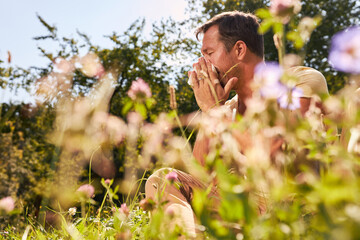 Man with hay fever blows his nose - obrazy, fototapety, plakaty
