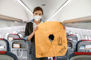 Female flight attendant in medial mask holding life vest