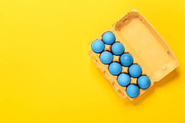 Package of chicken eggs painted in blue colors on yellow background. Copy space. Banner. Religion holiday concept. Mockup design. Neon minimalist style. Ukraine