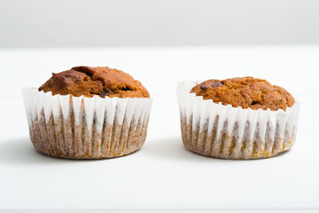 pair of chocolate muffins on white table