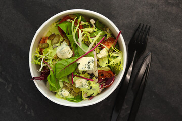 Healthy salad with beetroot, blue cheese, tomatoes, quinoa and 
pumpkin seeds in eco paper package for take away or food delivery isolated on black background. Top view. Keto diet.