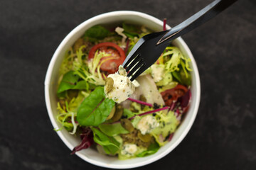 Healthy salad with beetroot, blue cheese, tomatoes, quinoa and 
pumpkin seeds in eco paper package for take away or food delivery isolated on black background. Top view. Keto diet.