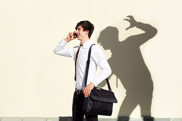 His fears are never far behind him. Shot of a young man being stalked by a ominous shadow of himself.