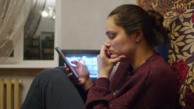 a sad girl watches the terrible news about the Russian offensive on the territory of Ukraine on a smartphone. News about tensions between Ukraine and Russia. Russian aggression. The threat of war