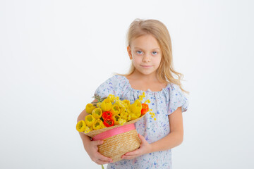 cute little blonde girl in a dress holding a bouquet of spring flowers on a white background. A child holds a bouquet of yellow tulips isolated on a white background.