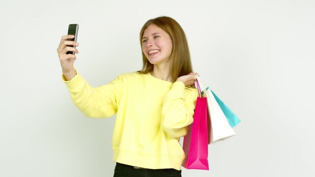 Young woman holding shopping bags while making a selfie isolated on background
