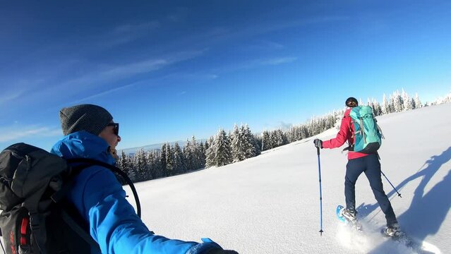 Happy couple walking in snow shoes near mount Teufelstein in Fischbach in Styria, Austria. Winter wonderland in Austrian Fischbach Alps. Sunny day. Outdoor activities. Fresh powder snow

