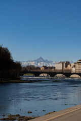 View of the Alps from the city of Torino. Next to the Po' River. Old buildings and Monviso in the background.