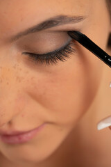 close up of a young woman applying eye shadow with a brush