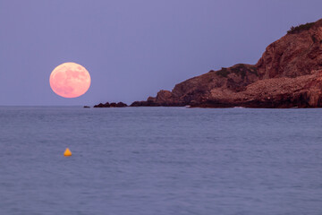 pink moon rising over the mediterranean sea from the beach of pals on the costa brava
