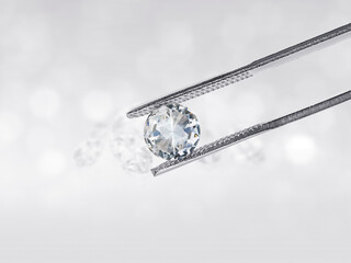 Dazzling diamond held in diamond tweezers in front of a white background, reflections on the ground. Lot of copyspace