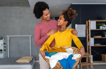 Happy black daughter helping mother do household and domestic chores together - obrazy, fototapety, plakaty
