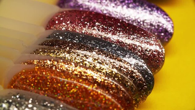 Package of nail tips with huge multicolored assortment of shiny varnishes lying on the table and filmed in macro. Glittering polish samples for making gel manicure. Glossy lacquers with flash pigment.